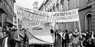 Zwei Männer halten ein Transparent auf dem steht: Ohnesorg, Dutschke - wen treffen die nächsten Schüsse der "Ordnungshüter" und Verführten, dahinter ist sind Demonstranten zu sehen, darunter auch eine Frau