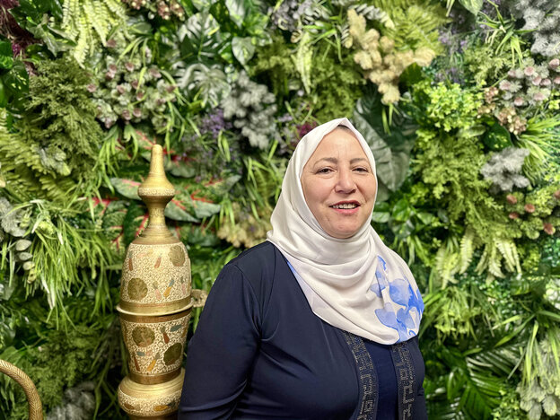 Saida Affouneh steht mit Kopftuch vor einer grünen Hecke