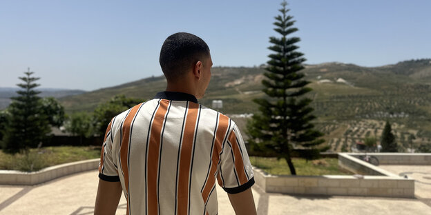 Ezz, ein junger Mann steht vor seinem Haus und schaut über eine Landschaft