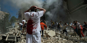 Ein Mann steht mit dem Rücken zur Kamera und blickt auf Trümmer einer Klinik