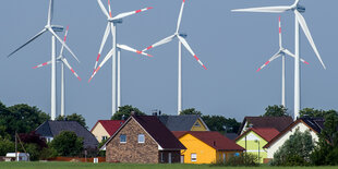 Bunte Einfamilienhäuser zu Füßen von Windrädern