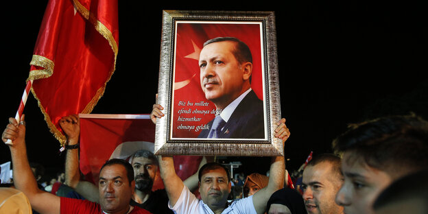 Ein Anhänger des türkischen Präsidenten Erdogan zeigt ein Erdogan-Portrait während einer Ansprache von Erdogan vor der offiziellen Residenz des Präsidenten in Istanbul im Juni 2018.