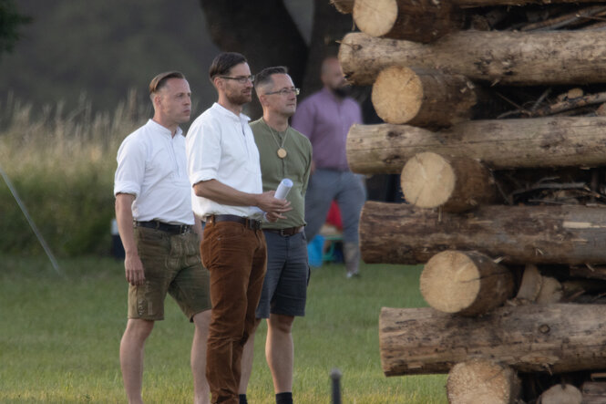 Neben einem Holzstapel stehen Stephan Jurisch, Robert Thieme und Thomas Christgen