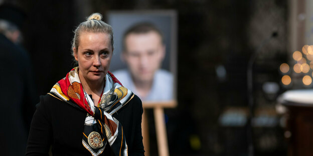 Julia Nawalnaja steht in Berlin vor einem unscharfen Porträt ihres Mannes Allexej Nawalny