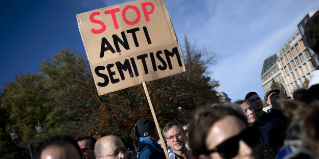 Demonstranten mit einem Schild, auf dem "Stop Antisemitism" steht