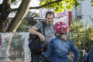 Ein Mann steht gegenüber einem Kind mit Fahrradhelm