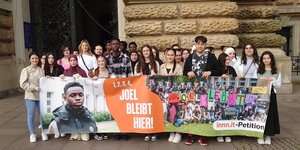 eine Gruppe Jugendlicher hält vor dem Hamburger Rathaus ein Banner mit der Aufschrift 1,2,3,4, Joel bleibt hier