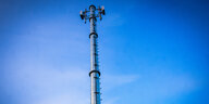 Mobilfunkantennen hängen an einem Mast vor blauem Himmel