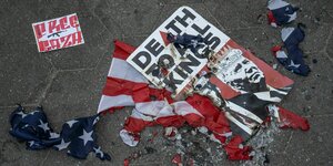Eine verbrannte amerikanische Flagge mit einem Schild mit der Aufschrift ?Tod allen Königen? und dem Foto von Präsident Biden und dem ehemaligen Präsidenten Trump . Darüber ein Zettel: Free Gaza mit MG Symbol
