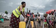 Eine Frau befüllt Wasserkanister an einer Wasserstelle in einem Lager für geflüchtete