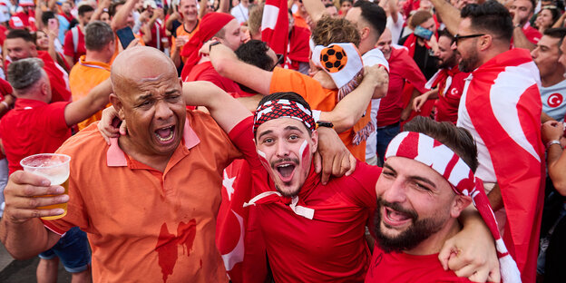 Türkische und niederländische Fussballfans liegen sich in den Armen und feiern gemeinsam