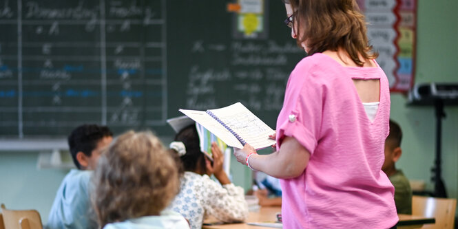 Schülerinnen und eine Erzieherin in einem Schulraum mit Tafel