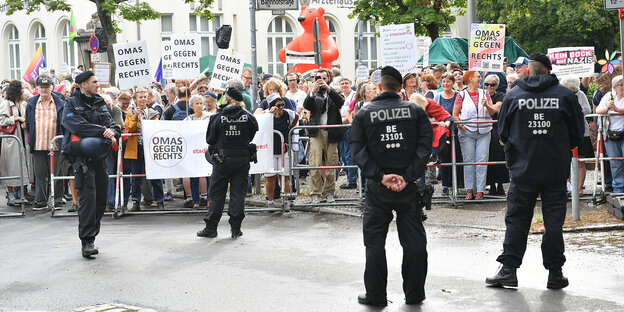 Ganz viele Menschen, die gegen Nazis demonstrieren, hinter einer Absperrung. Davor: einige Polizeibeamten
