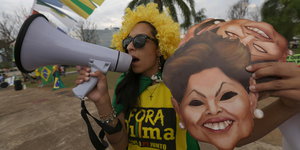 Demonstrantin mit Megafon und Rousseff-Masken in der Hand