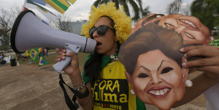 Demonstrantin mit Megafon und Rousseff-Masken in der Hand