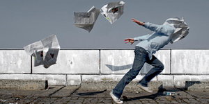 Mensch rennt gegen fliegende Zeitungen an