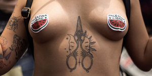 Eine nackte Demonstrantin mit pro-Palästina-Aufklebern auf den Brustwarzen
