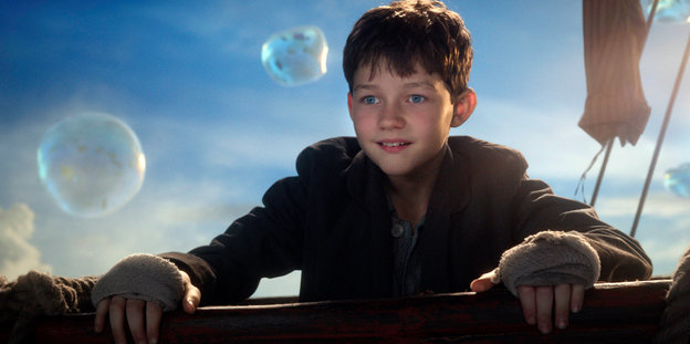 Levi Miller als Peter Pan steht an der Reling und staunt über vorbeischwebende Blasen