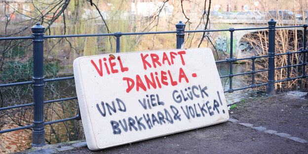 Auf einer Matratze an einem Kanal steht: "Viel Kraft Daniela und viel Glück Burkhard & Volker"