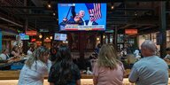 Menschen schauen auf einen Fernsehschirm, auf dem Donald Trump zu sehen ist