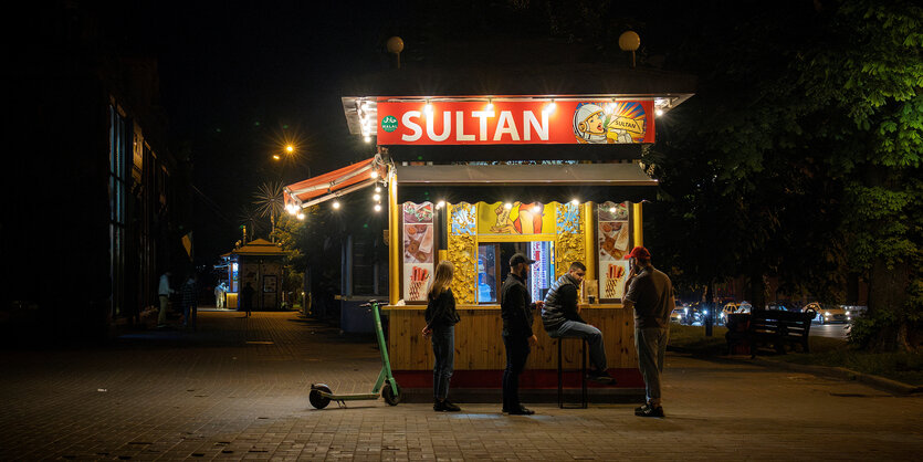 Menschen stehen an einem Fast-Food-Stand in der Chreschatyk-Straße, der Haupteinkaufsmeile der Hauptstadt, während eines teilweisen Stromausfalls inmitten des russischen Angriffs auf die Ukraine, in Kiew, Ukraine, 16. Mai 2024.