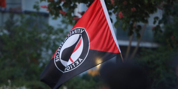 Eine Antifa-Fahne wird während einer Demonstration zum 1.Mai in die Höhe gehalten.