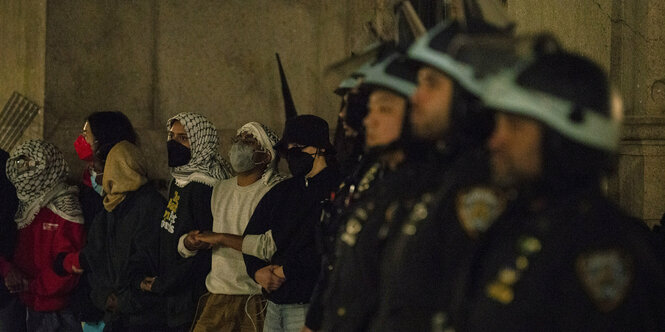 Eine Reihe von Polizisten steht neben Protestierenden