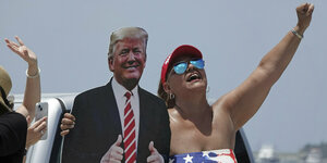 Frau hält Pappform von Donald Trump hoch.