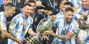 Argentinische Fußballspieler im blau-weißen Trikot jubelnd mit Pokal in den Händen