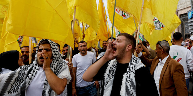Zwei junge Männer mit gelben Flaggen und Palästinensertüchern auf einer Demo