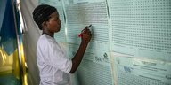 Eine Frau schreibt an eine Wand mit Wahlergebnissen in Ruanda