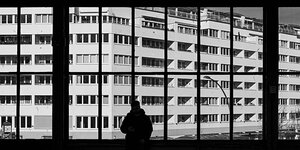Ein Mann steht am Fenster im U-Bahnhof Nollendorfplatz und blickt auf einen Wohnblock.