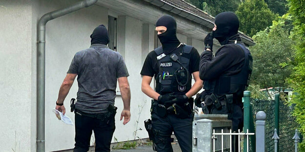 Vermummte Polizisten stehen vor einem Wohnhaus in Brandenburg