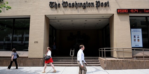Drei Personen vor einem Gebäude mit der Aufschrift "Washington Post".
