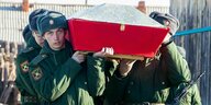 Junge Soldaten tragen den roten Sarg eines getöteten Soldaten