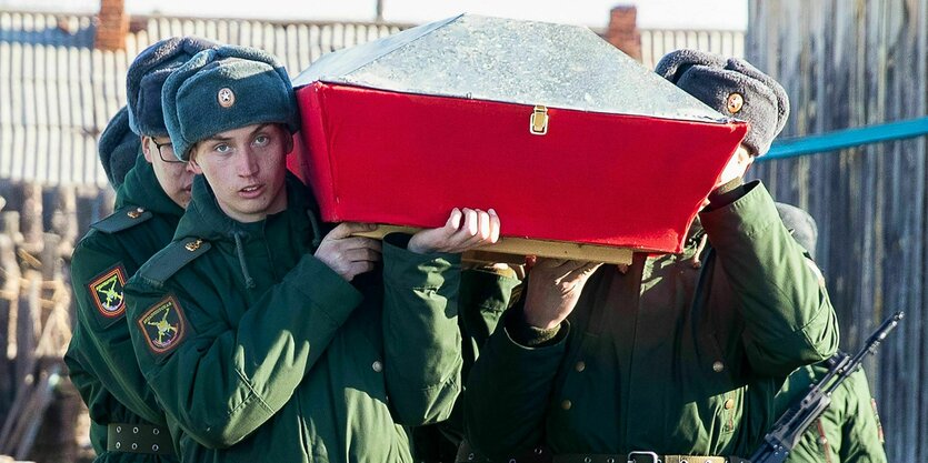 Junge Soldaten tragen den roten Sarg eines getöteten Soldaten