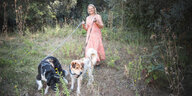 Eine Frau geht mit zwei Hunden spatzieren
