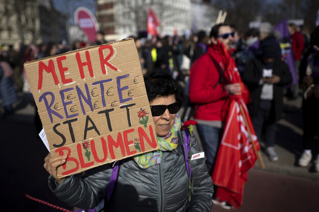 Eine Frau im fortgeschrittenen Alter geht auf einer Demo zum Frauentag. In der Hand hält sie ein Schild aus Pappe. 