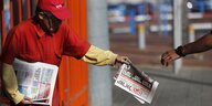 Ein älterer Mann im roten T-Shirt verteilt die Zeitung: Israel Hayom. Eine Hand greift nach einem Exemplar