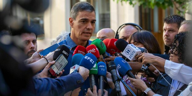 Pedro Sanchez spricht nach seiner Stimmabgabe mit der Presse, viele Mikrofone werden ihm entgegengehalten