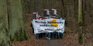 Eine Gruppe läuft mit einem Transparent durch einen herbstlichen Wald Auf dem Transparent Rechte Netzwerke aufdecken No compact