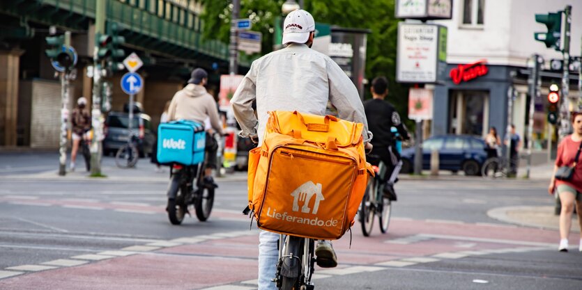 Lieferando und Wolt-Lieferer fahren mit dem Fahrrad auf der Schönhauser Allee beim Bahnhof Eberswalder Strasse in Berlin