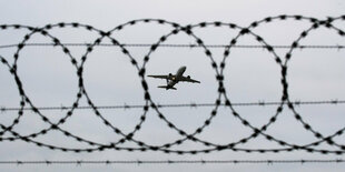 in Flugzeug startet - fotografiert durch Stacheldraht