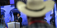 Eine Person mit Cowboyhut im Vordergrund blickt auf eine Person an einem Rednerpult
