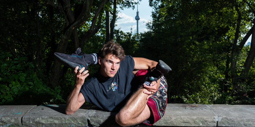 Moritz Haase mit einem Bein hinterm Kopf, im Hintergrund ist der Berliner Fernsehturm zu sehen