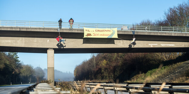 Aktivisten hängen Transparente von einer Autobahnbrücke und seilen sich daneben ab