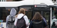 Drei Schüler:innen stehen vor einem Hamburger Bus