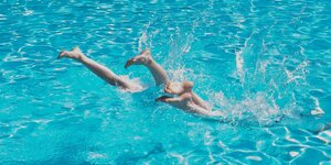 Füsse von zwei Kindern die gerade in ein Schwimmbecken gesprungen sind