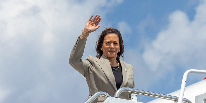 Kamala Harris, eine Frau mit braunen Haaren, winkt.