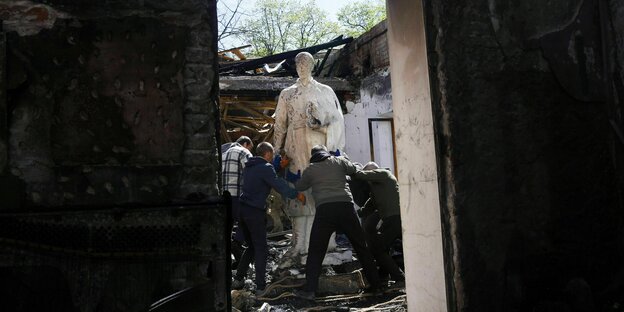 Nach einem russischen Bombenangriff auf das Gregorius-Skoworoda-Museum nahe Charkiw holen Mitarbeiter eine Statue des Philosophen aus den Trümmern